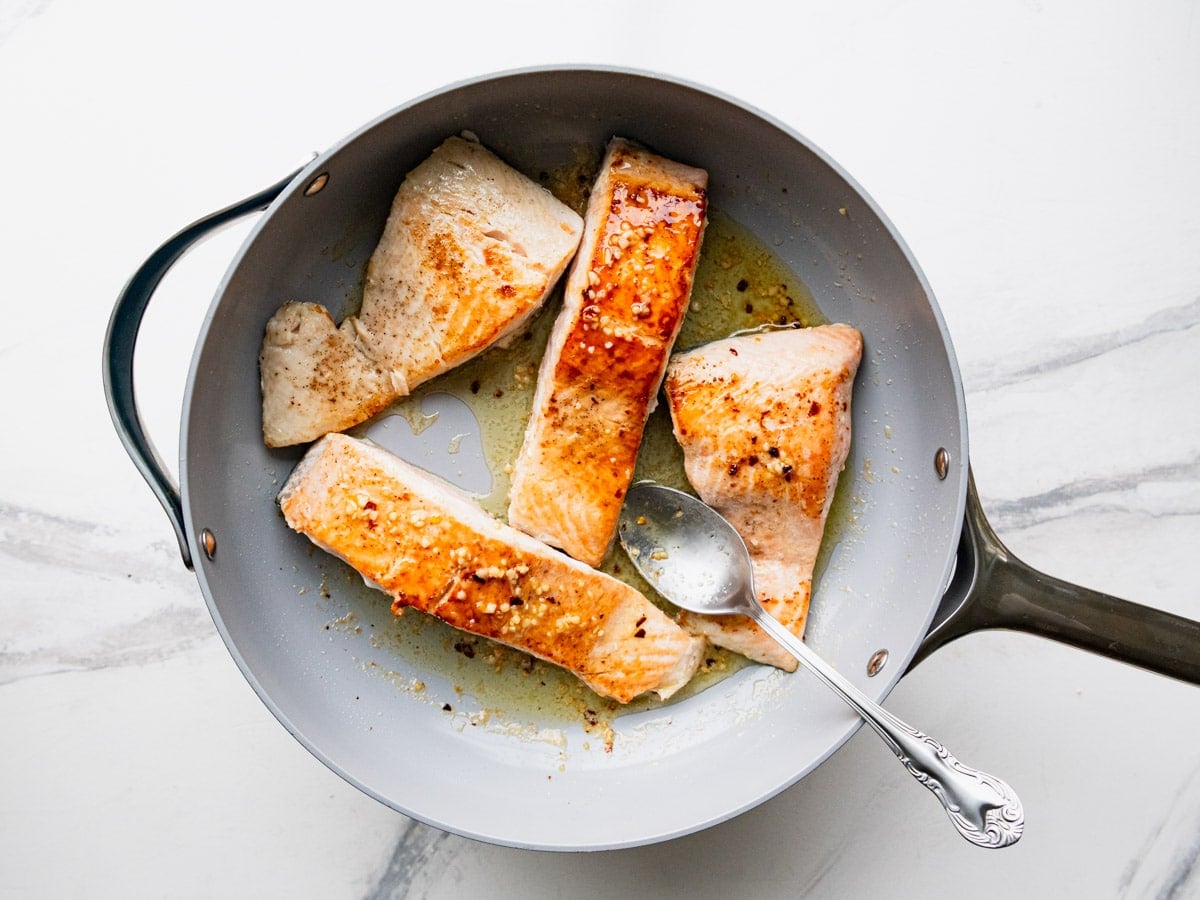 Pan seared garlic butter salmon in a skillet.