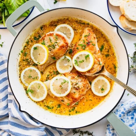 Square overhead shot of skillet lemon chicken on a white table.