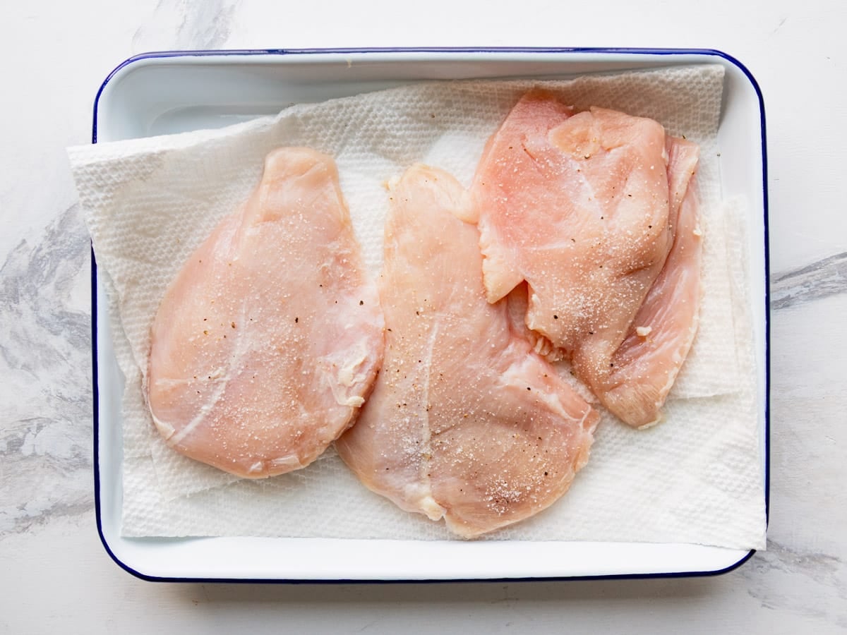 Seasoning chicken cutlets.