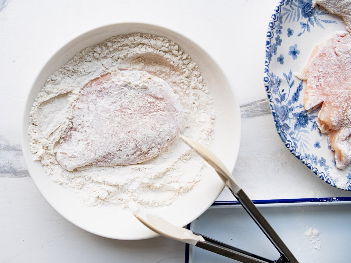 Dredging chicken cutlets in flour.