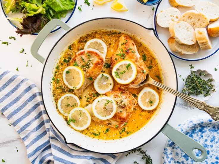 Horizontal overhead shot of skillet lemon chicken on a white table.