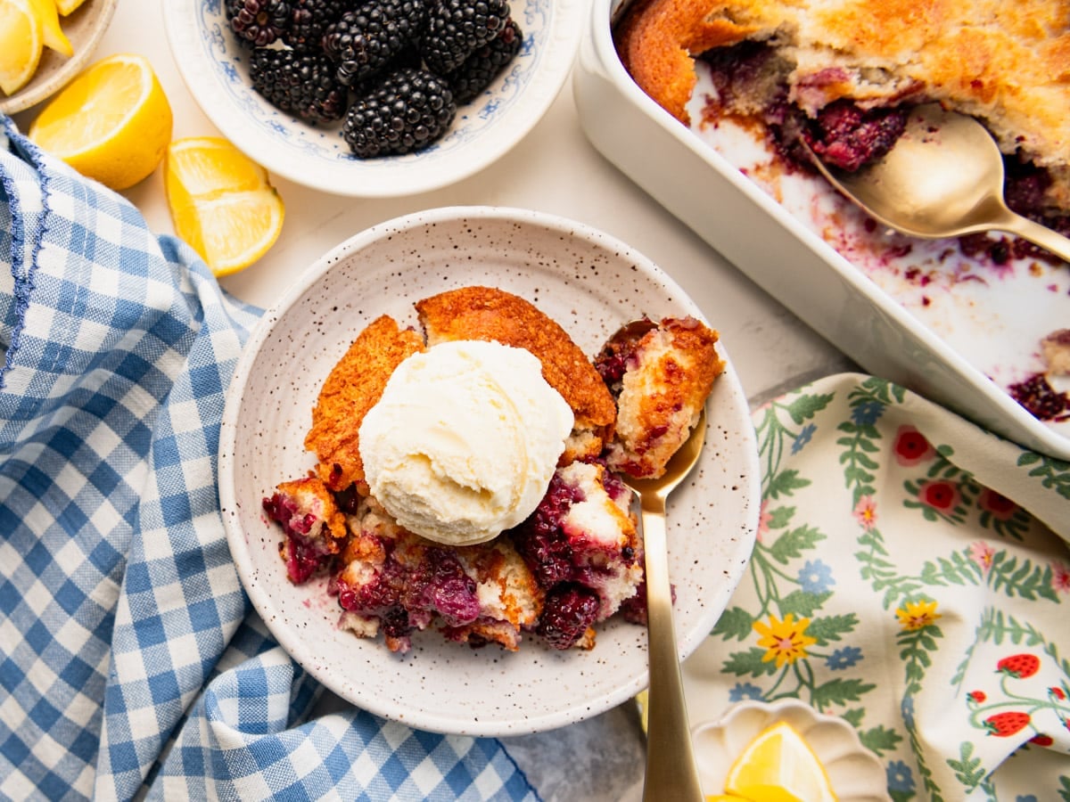 Horizontal overhead shot of a bowl of blackberry cobbler with vanilla ice cream on top.