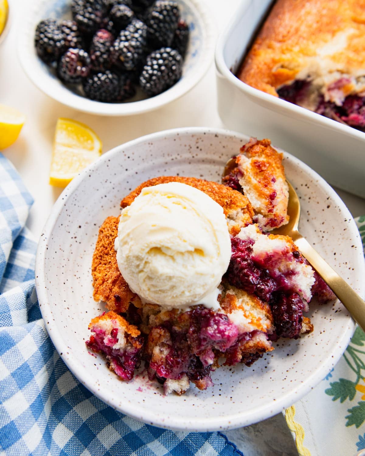 Side shot of a bowl of blackberry cobbler with a scoop of vanilla ice cream.
