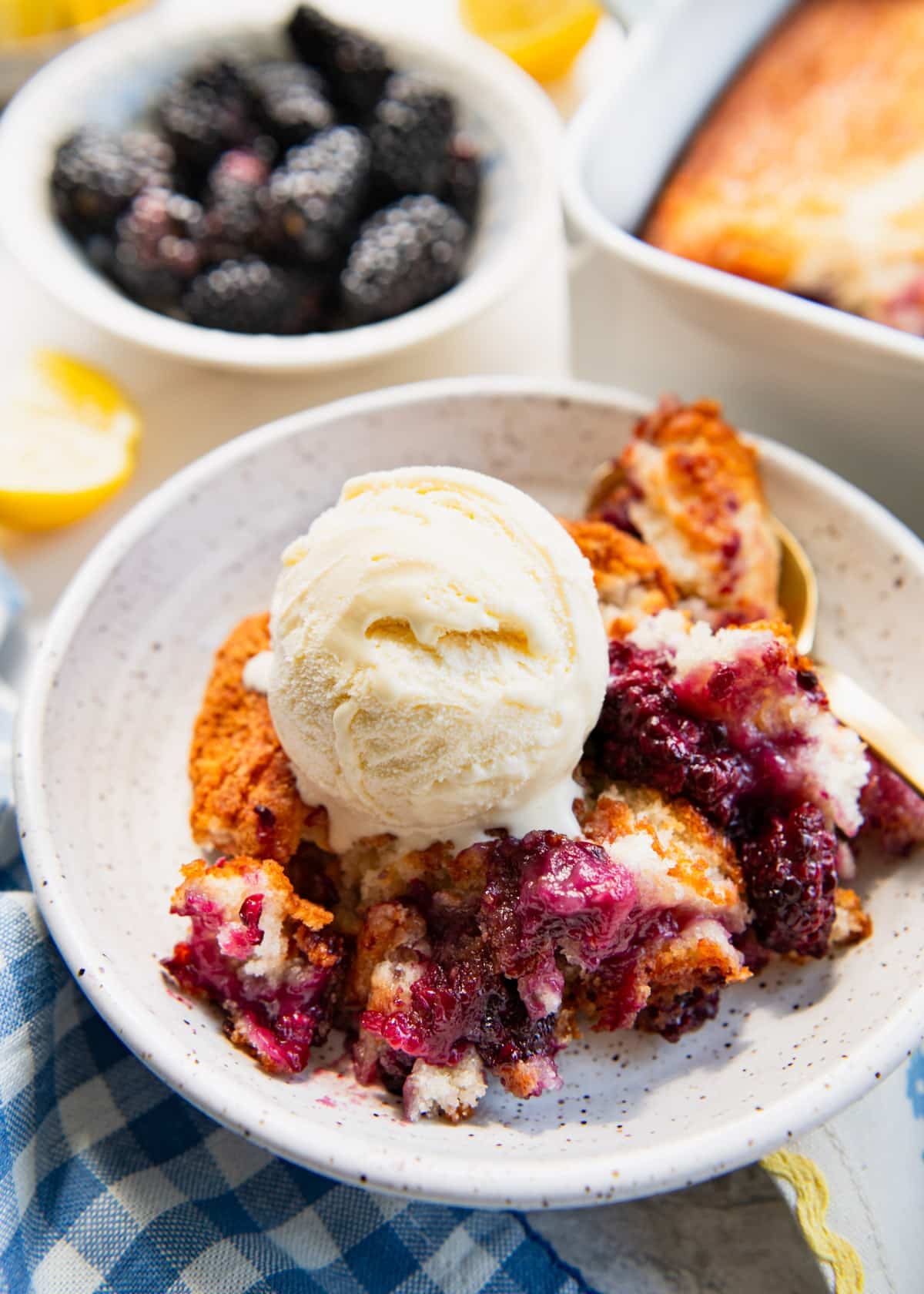 Close up side shot of a bowl of blackberry cobbler with a scoop of vanilla ice cream.