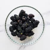 Fresh blackberries in a bowl with lemon zest and lemon juice.