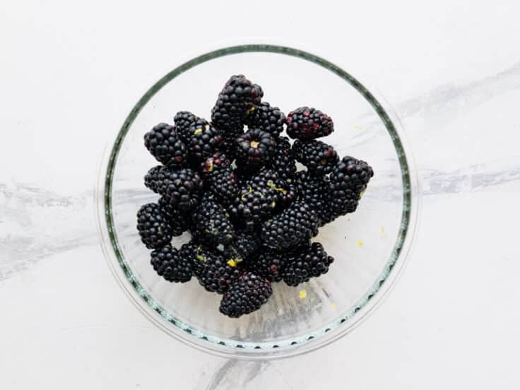 Fresh blackberries in a bowl with lemon zest and lemon juice.