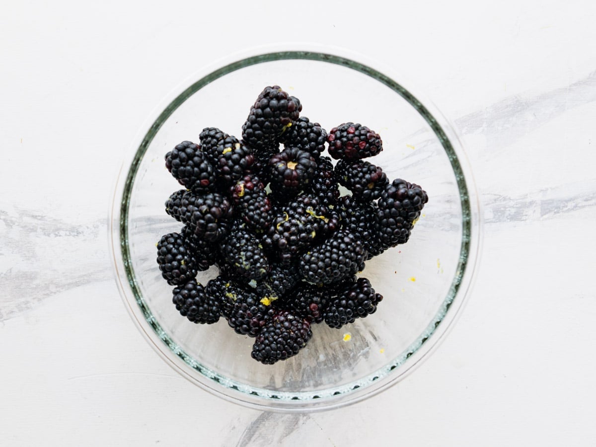 Fresh blackberries in a bowl with lemon zest and lemon juice.