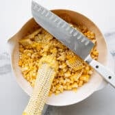 Cutting the kernels off of corn cobs.