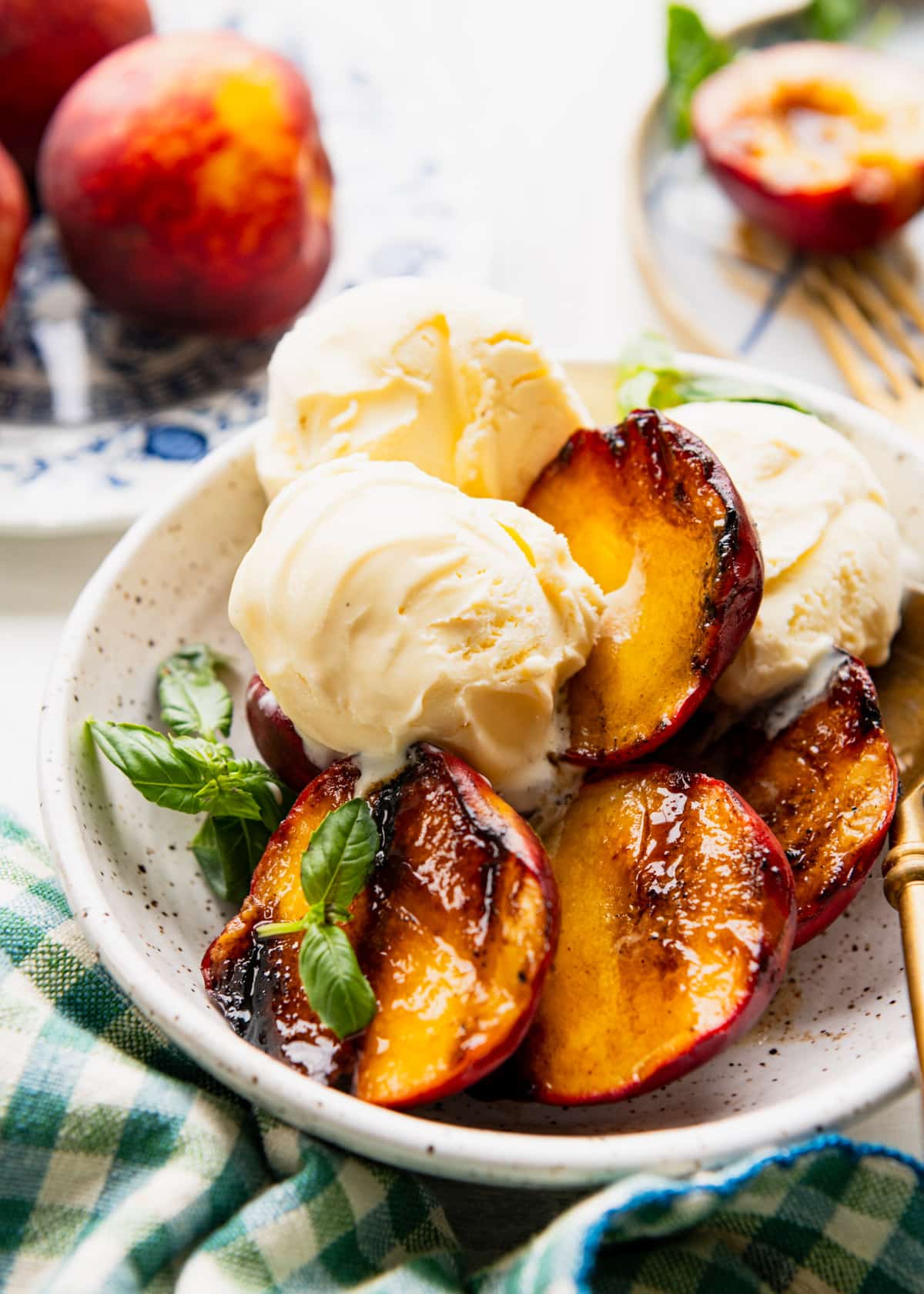 Bowl of fresh grilled peaches with vanilla ice cream and basil.