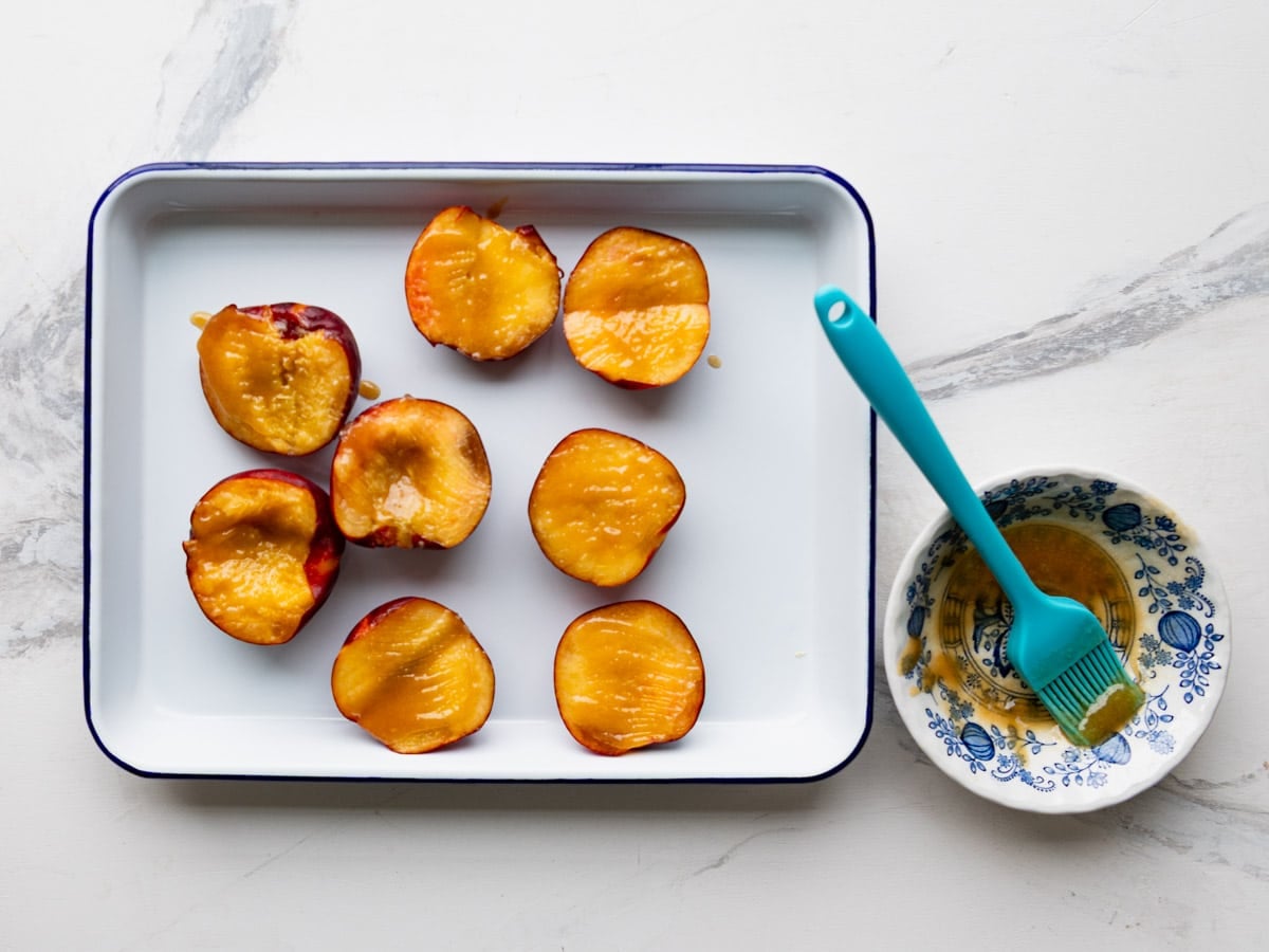 Brushing peaches with the melted butter mixture.