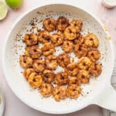 Searing seasoned shrimp in a skillet.