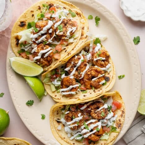 Square overhead shot of easy shrimp tacos on a white oval platter.