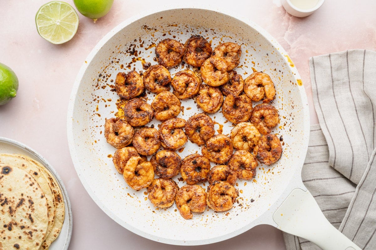 Searing seasoned shrimp in a skillet.