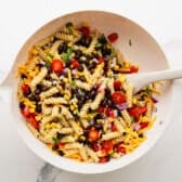 Adding corn, beans, and other ingredients to the cooked pasta.