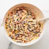 Combining the pasta salad ingredients with the dressing.