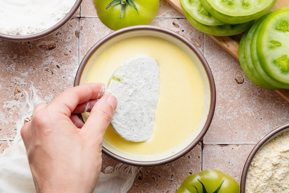 Dipping the flour coated slice in the egg and buttermilk mixture.