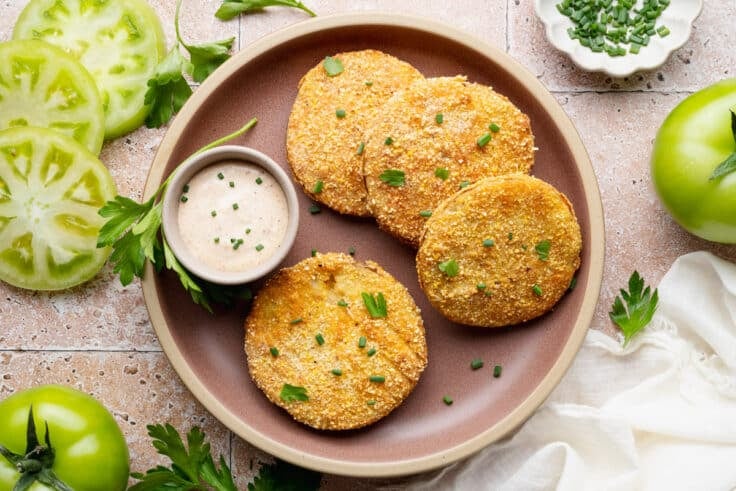 Horizontal overhead shot of fried green tomatoes on a plate with a side of creamy remoulade sauce.