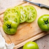Slicing green tomatoes on a cutting board.