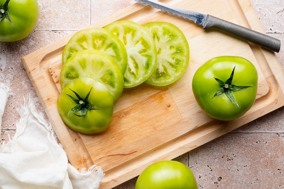 Slicing green tomatoes on a cutting board.