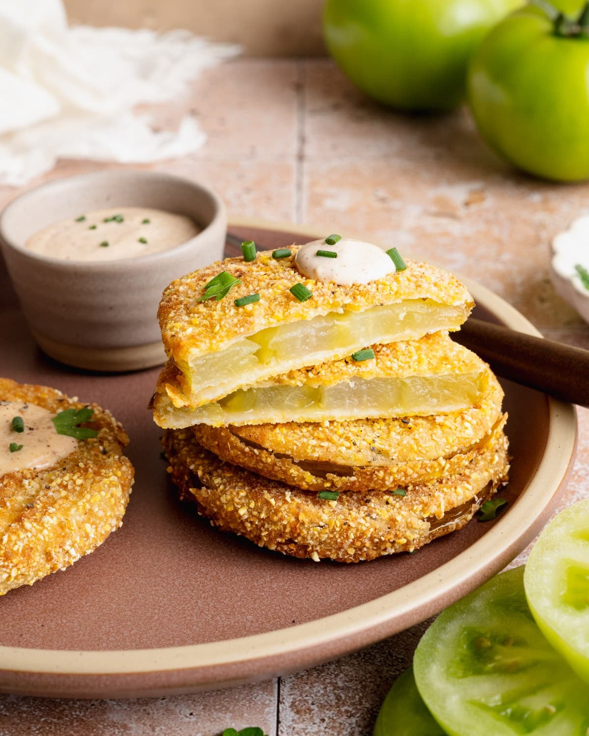 Side shot of sliced Southern fried green tomatoes on a plate so that you can see the inside.