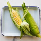 Removing the corn silk from an ear of corn.