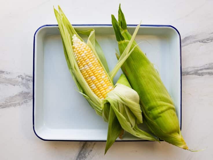 Removing the corn silk from an ear of corn.