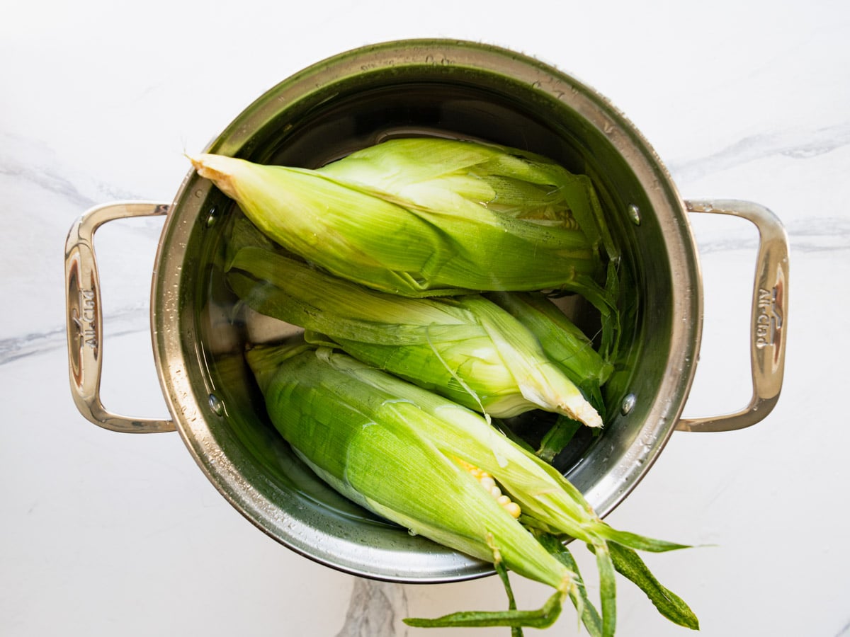 Soaking ears of corn in water.