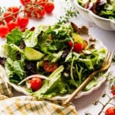 Horizontal side shot of a side salad on a white table.