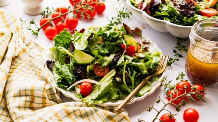 Horizontal side shot of a side salad on a white table.
