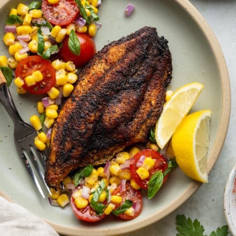 Blackened catfish on a plate with corn salad.
