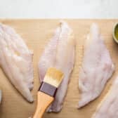 Brushing catfish fillets with melted butter.