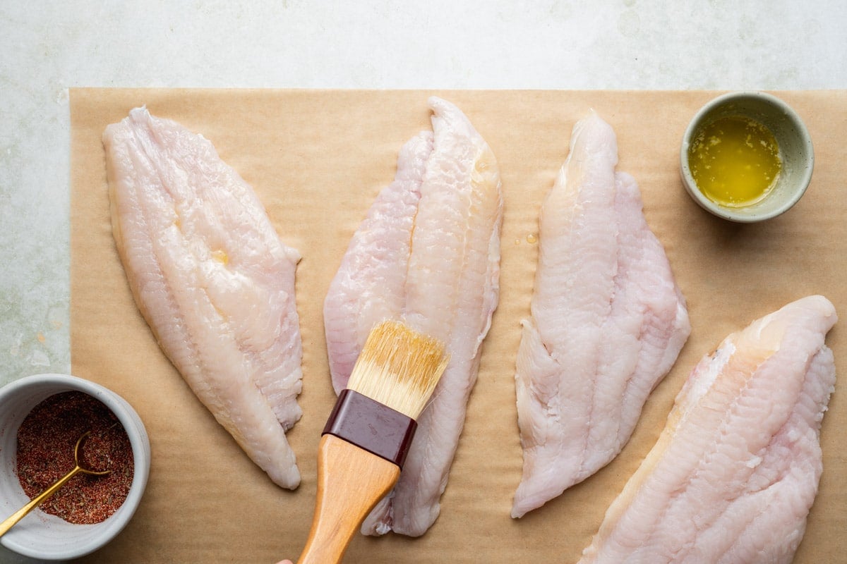 Brushing catfish fillets with melted butter.