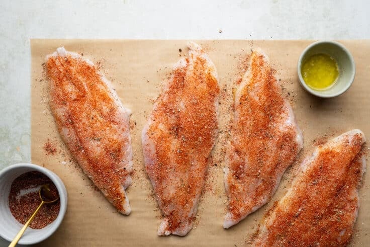 Rubbing blackened seasoning on catfish fillets.