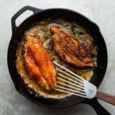 Flipping blackened catfish fillets in a cast iron sklilet.