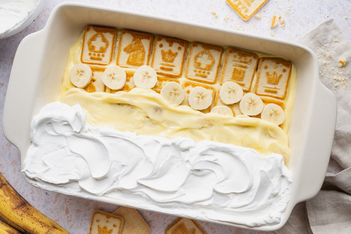 Horizontal overhead shot showing how to layer the ingredients for an easy no bake chessman banana pudding recipe.