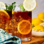 Square side shot of glasses of sun tea with lemon wedges and fresh mint.