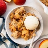 Horizontal overhead shot of a bowl of apple crumble with a scoop of vanilla ice cream on top.