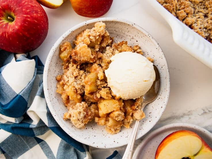 Horizontal overhead shot of a bowl of apple crumble with a scoop of vanilla ice cream on top.