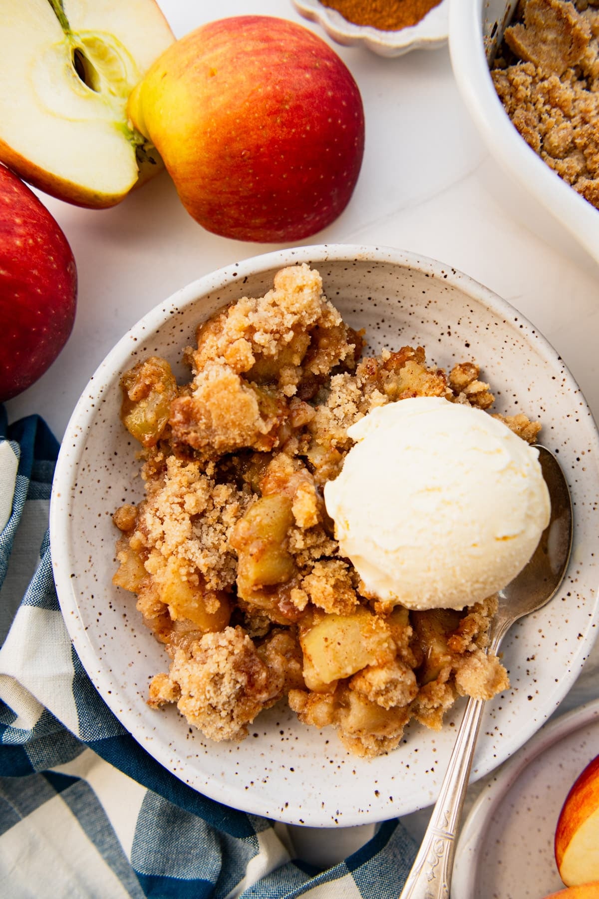 Overhead shot of a bowl of apple crumble with a scoop of vanilla ice cream on top.