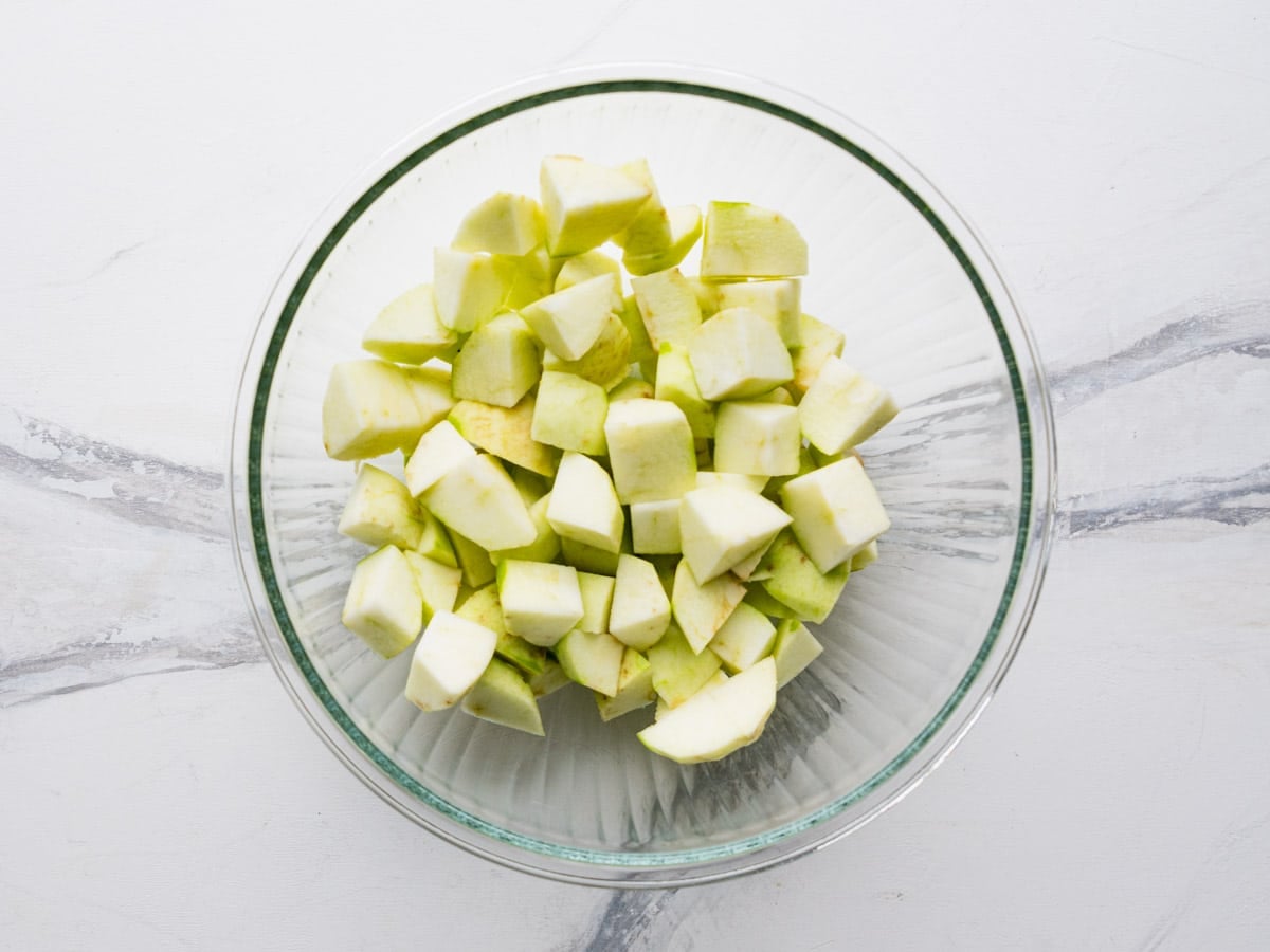 Peeled and diced apples in a glass bowl.