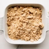 Adding the topping to an apple crumble before it goes in the oven.