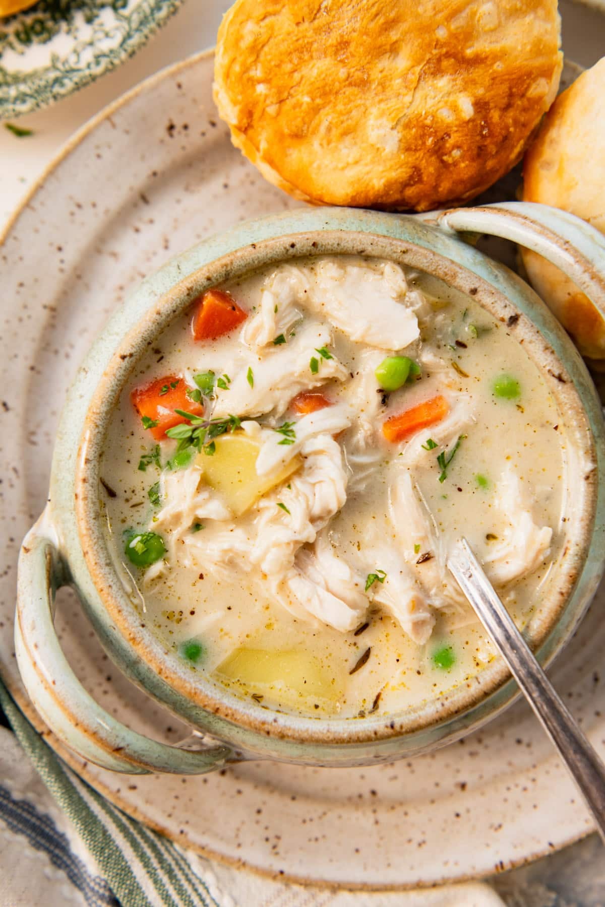 Close overhead shot of a bowl of chicken pot pie soup with biscuits on the side.