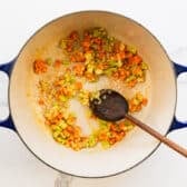 Sprinkling flour into the Dutch oven to make a roux for the soup.