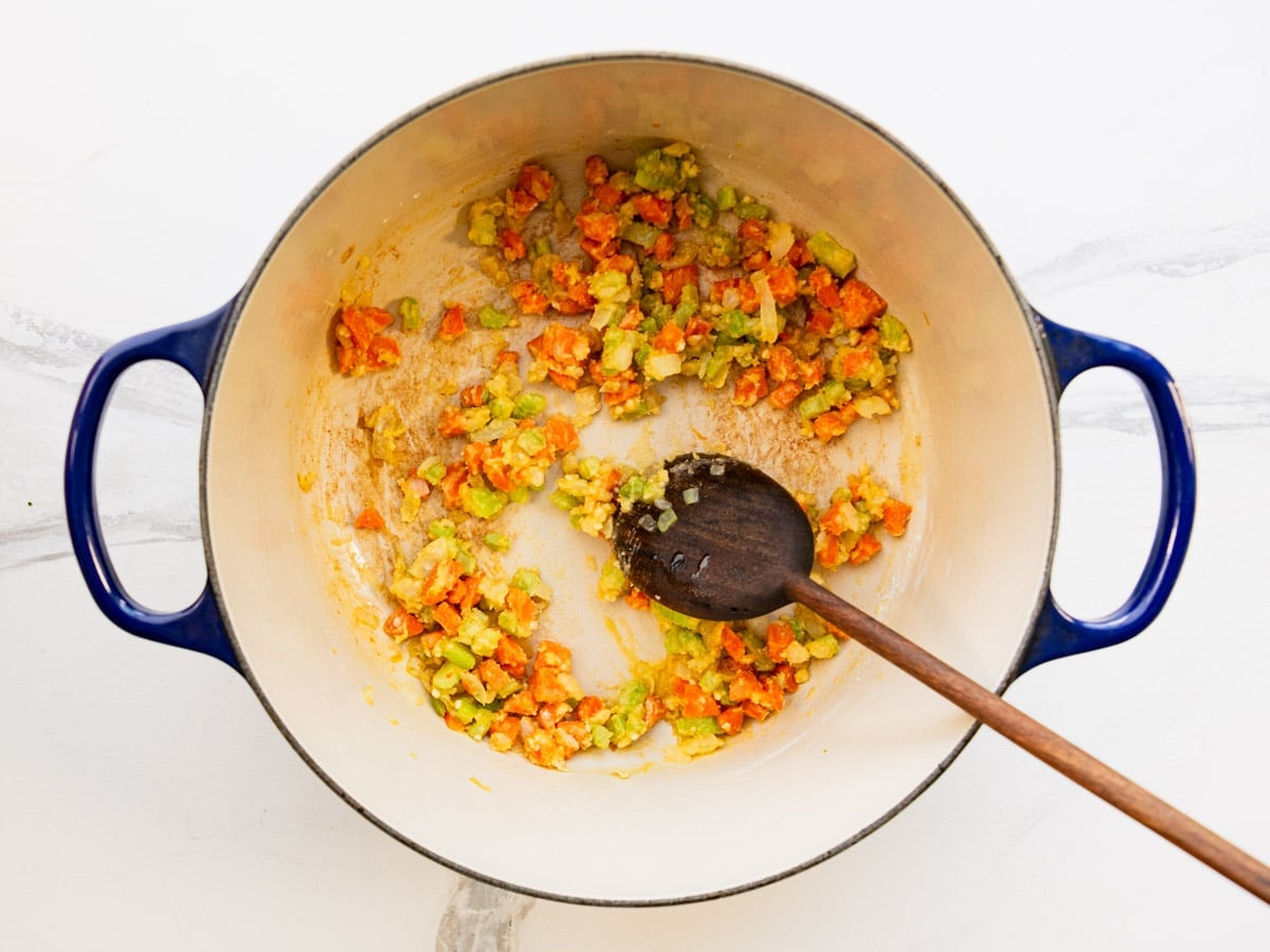 Sprinkling flour into the Dutch oven to make a roux for the soup.