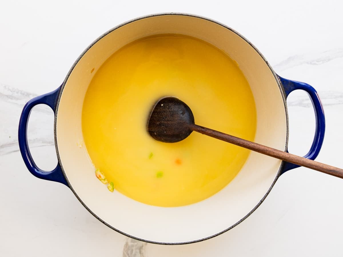 Adding broth and potatoes to the pot.