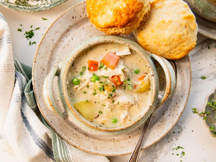 Horizontal overhead chicken pot pie soup with biscuits on the side.