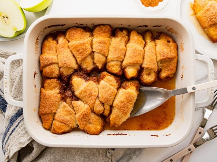 Horizontal overhead shot of a white baking dish full of baked crescent roll apple dumplings.
