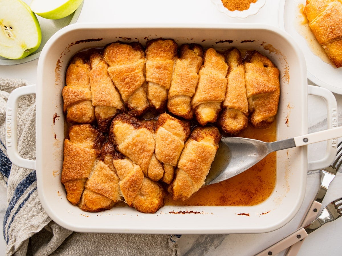 Horizontal overhead shot of a white baking dish full of baked crescent roll apple dumplings.