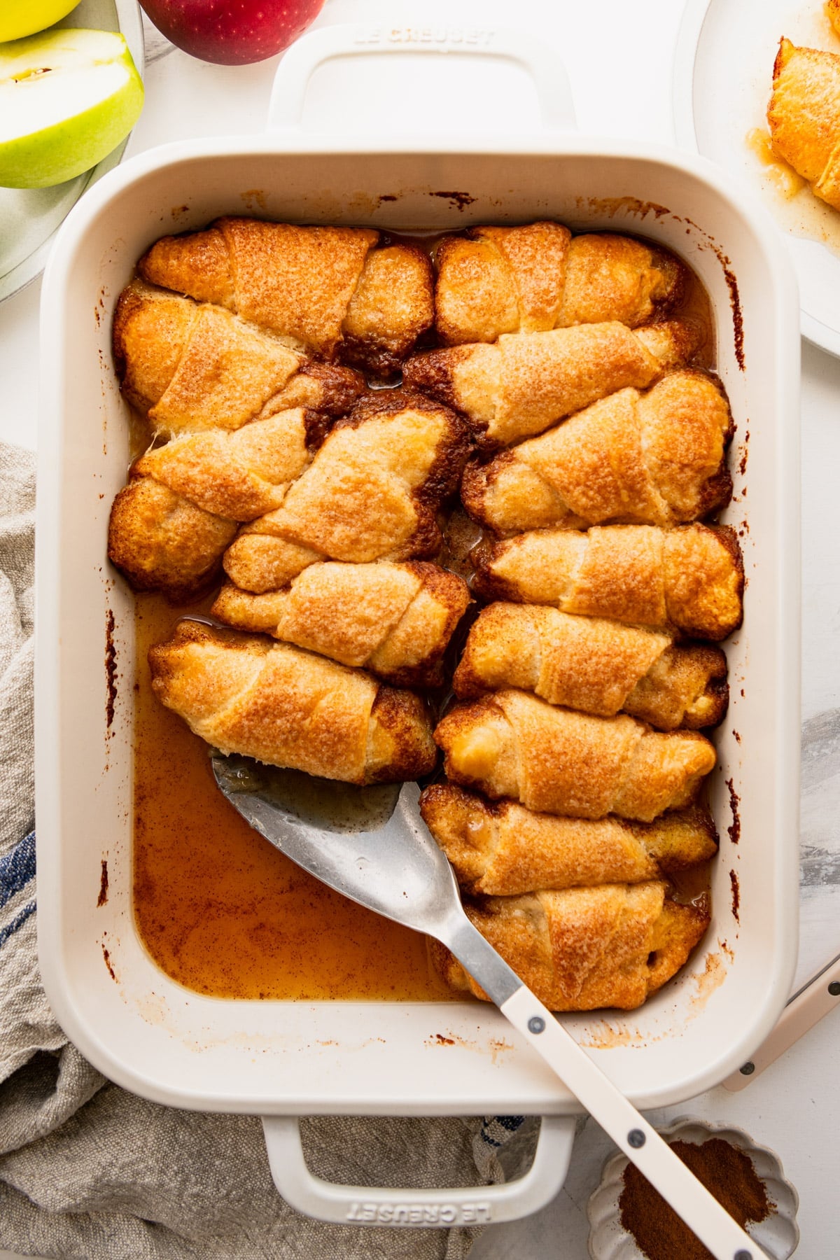 Overhead shot of a white baking dish full of baked crescent roll apple dumplings.