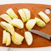 Peeled and sliced Granny Smith apples on a cutting board.